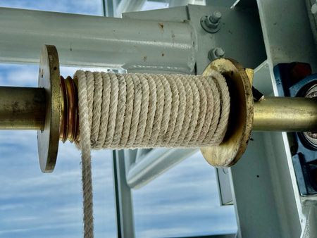 Close-up of a white rope wound on a brass winch spool, showing detailed industrial equipment design and mechanical texture under natural light.の写真素材