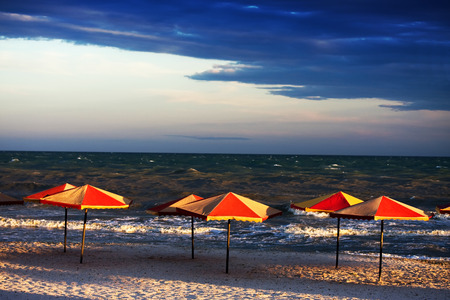 Empty beach with umbrellas in bad, stormy weatherの写真素材