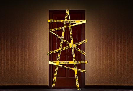 Dramatic image of a closed door in the house, which is blocked by yellow police tape with the requirement not to enterの写真素材