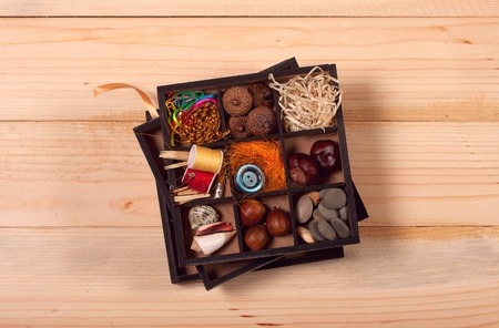 Kids set for creativity of chestnuts, acorns, thread, straw and stones on wooden tableの写真素材