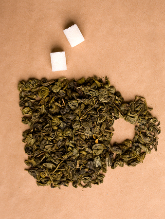 Dried leaves of green tea lined in the form of a cup on a beige background of kraft paperの写真素材
