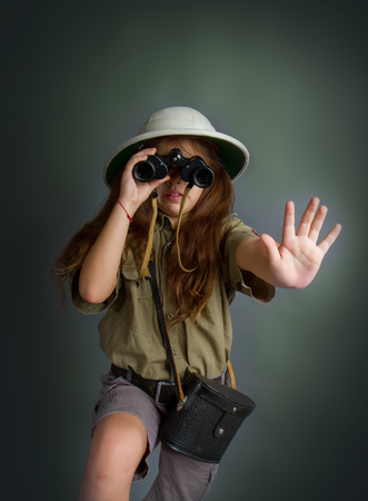 little girl in tropical uniform and cork helmet looks through binocularsの写真素材
