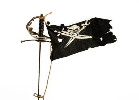 Black pirate flag winding up in the wind tied with a rope to an old swordの写真素材