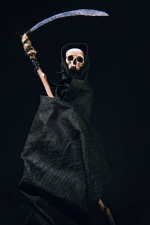 conventional death symbol with a slanting skull in a dark robe with a hood on a dark backgroundの写真素材