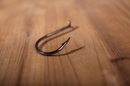 sharp steel big empty fishing hook on a wooden surfaceの写真素材