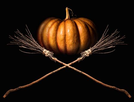 big orange pumpkin and two witches classic crossed brooms on a dark backgroundの写真素材