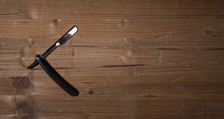 sharp open straight razor lying on a rough wooden backgroundの写真素材