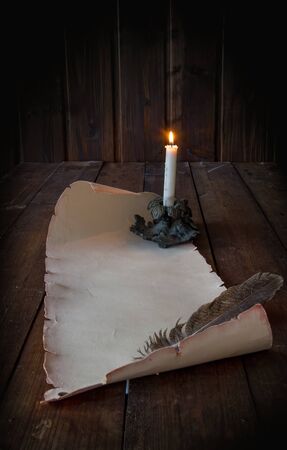 vintage paper scroll on a wooden table a feather for writing by candlelightの写真素材