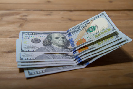 five hundred dollar bills lying on a rough wooden surface