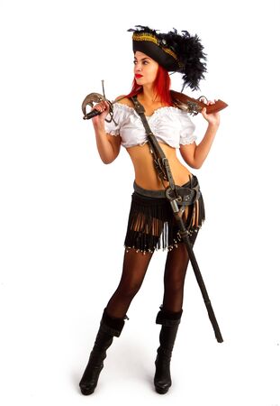 sexy girl in a pirate costume and a cocked hat stands armed with a gun and a sword on a white backgroundの写真素材