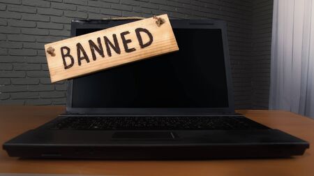 turned off laptop with a wooden sign that says bannedの写真素材
