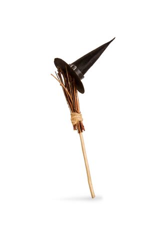 classic witch pointed black wide-brimmed hat hanging on a wooden broomstick for flyingの写真素材