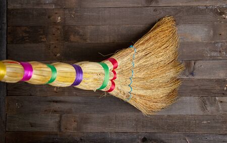 old broom that sweeps a dark rough wooden floorの写真素材