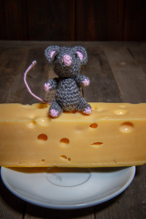 a small toy mouse the symbol of 2020 sits on a large piece of cheese with holes in a dark roomの写真素材