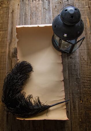 Empty paper vintage scroll under the light of a lantern and a black ostrich feather for writing nearの写真素材