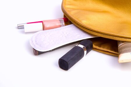 White feminine sanitary pad falling out of a cosmetic bag along with a variety of contentsの写真素材