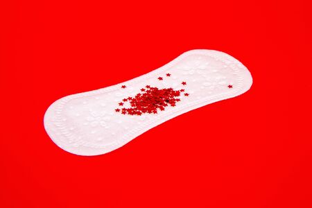 White feminine sanitary pad with impromptu monthly discharge on a bright red backgroundの写真素材