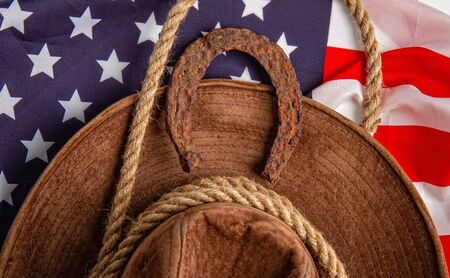very old and rusty horseshoe symbol of good luck and lasso and Cowboy Hat on the star-striped flag of the United States of Americaの写真素材
