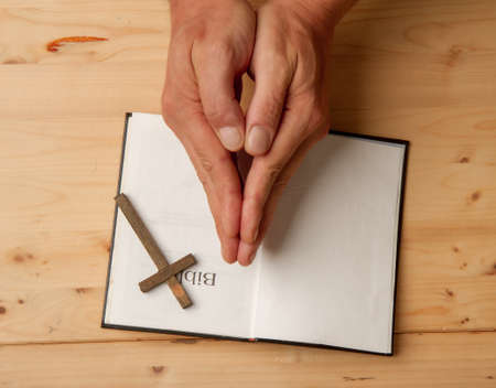 Man reading holy bible close-up on wooden background top viewの写真素材