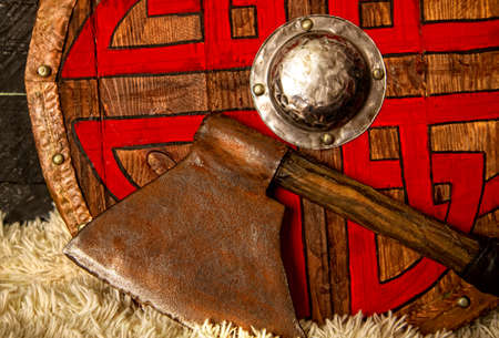 steel ax and wooden viking shield with pattern close upの写真素材