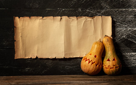 two festive Halloween pumpkins with different emotions on the background of a paper sheet with a...