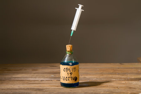 Dirty artisanal bottle with a fake coronavirus vaccine made in unsanitary conditions and a syringeの写真素材
