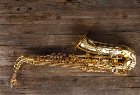 graceful classical musical instrument bronze saxophone on old wooden backgroundの写真素材