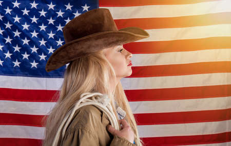 A blonde patriotic lady in a cowboy hat and with a lasso standsの写真素材