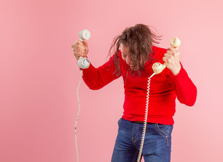 Adult male call center worker in casual clothes answers phone calls very emotionally