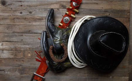 leather classic cowboy hat with lasso and horseshoe on rough wooden tableの写真素材