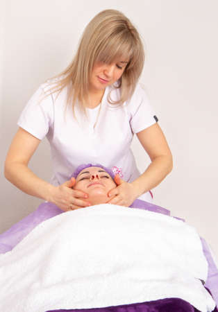 The specialist gives the girl massage and spa treatments for beauty and rejuvenation in the officeの写真素材