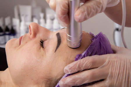 The specialist gives the girl massage and spa treatments for beauty and rejuvenation in the officeの写真素材