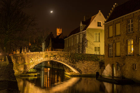 A canal in Bruges at night with illuminated bridgesの写真素材