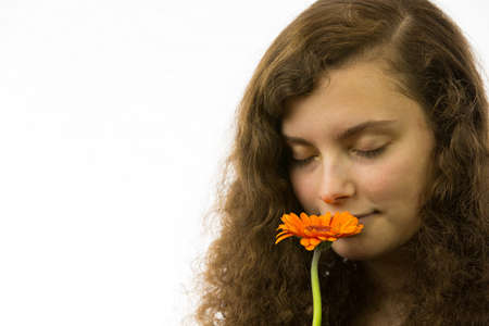 A young pretty woman holding a flower and taking a smellの写真素材