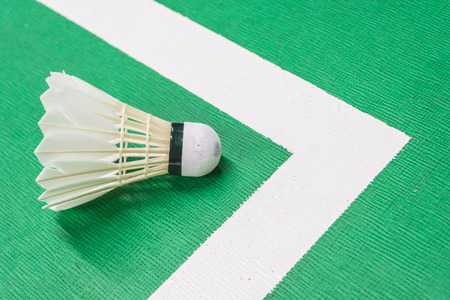 White badminton shuttlecock on a green court with a white line.の写真素材