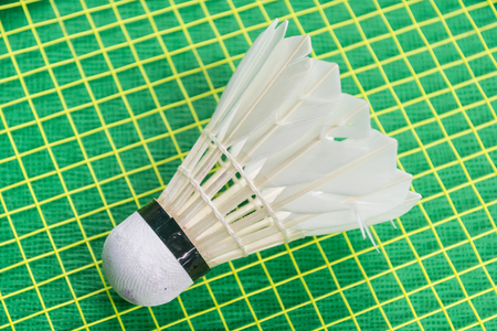 White shuttlecock on yellow racket net and green floor.の写真素材