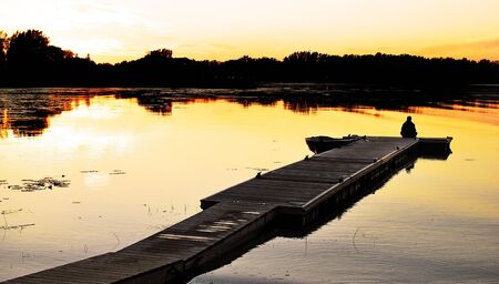Image of someone relaxing at the end of a dock enjoying the sunsetの写真素材