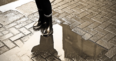 An image of someone standing in a puddle with rain boots onの写真素材