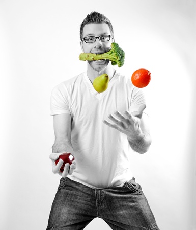Image of a man juggling fruits and vegetablesの写真素材