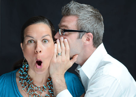 Image of a man telling a secret to a woman
