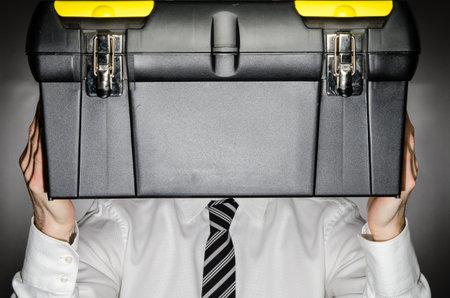Man wearing a tie holding a toolbox