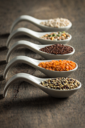 A variety of grains in spoons on woodの写真素材