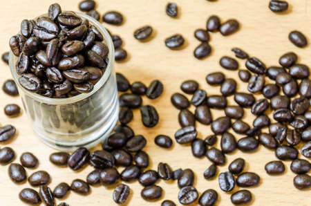 Coffee beans in a glass shot, with wooden floor backgroundの写真素材