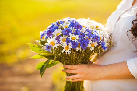 A pregnant woman with a bouquet of forest flowersの写真素材
