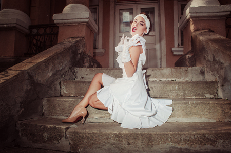 Girl sitting on stairs of old, blinks, smiles, gesturesの写真素材