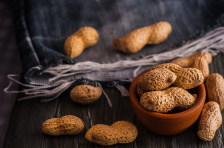 Peanuts in nutshell on a piece of wood.Many roasted peanuts on the wooden texture
