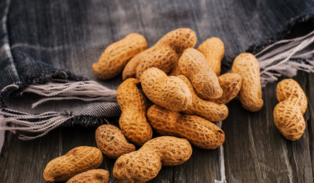 Peanuts in nutshell on a piece of wood.Many roasted peanuts on the wooden textureの写真素材