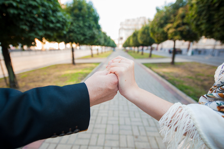 Hands newlyweds with wedding rings on background.people on the background of the parkの写真素材