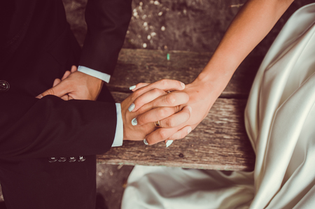 Hands newlyweds with wedding rings on background wooden textureの写真素材