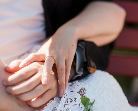 Hands newlyweds with wedding rings on background wooden textureの写真素材